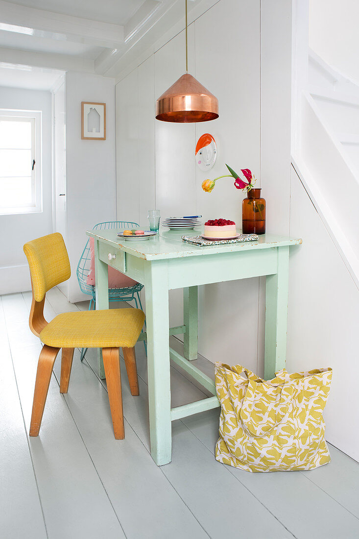 Gelber Stuhl am grün lackierter Küchentisch, darüber Kupfer-Pendelleuchte