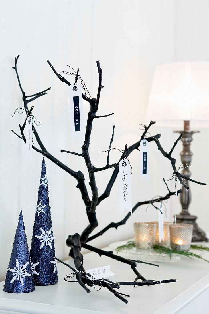 Stilisierte Weihnachtsbäume aus Pappkegeln und Ast mit Weihnachtsgrüßen