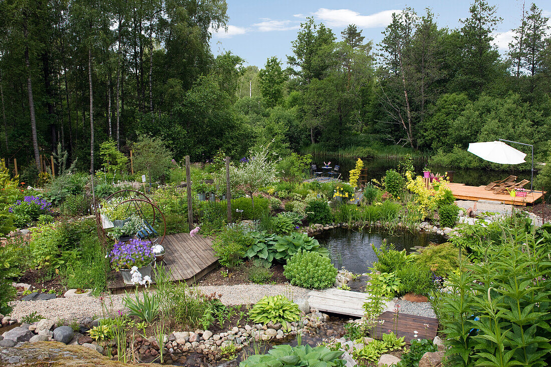 Gartenteich mit Steineinfassung, Holzstegen, Kieswegen und Sonnendeck