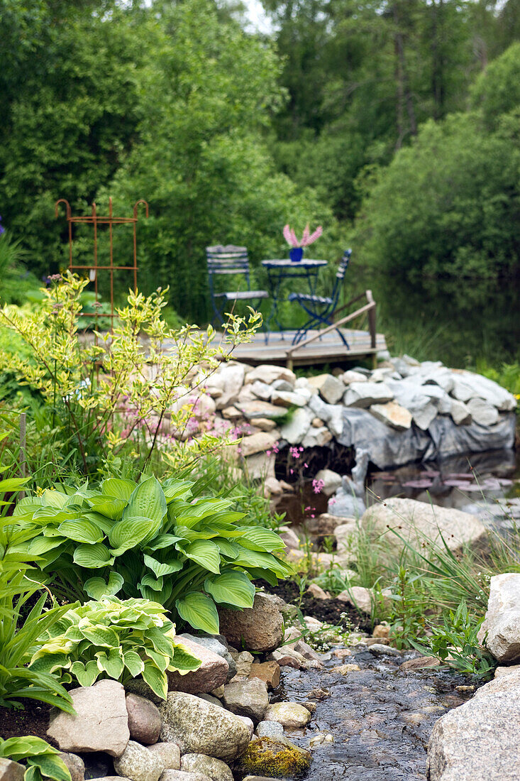 Gartenteich mit Wasserlauf, Steineinfassung und Holzdeck