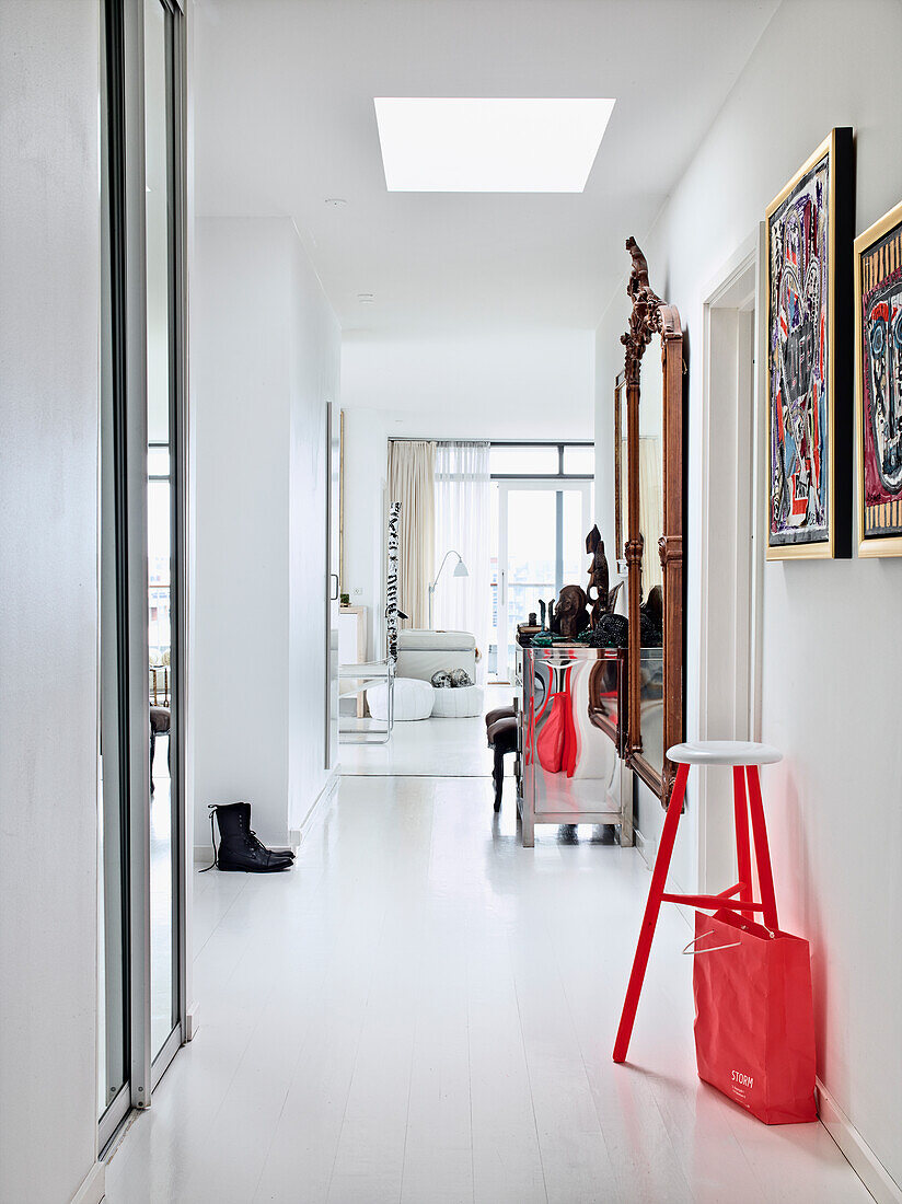 Rot-weißer Barhocker unter Kunstwerken in weißer Eingangshalle