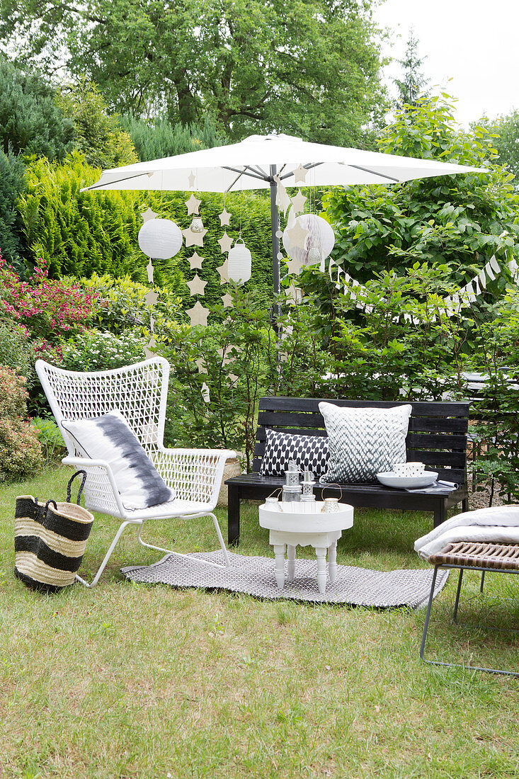 Schwarz-weiße Outdoormöbel, Sonnenschirm und Partydeko in sommerlichem Garten