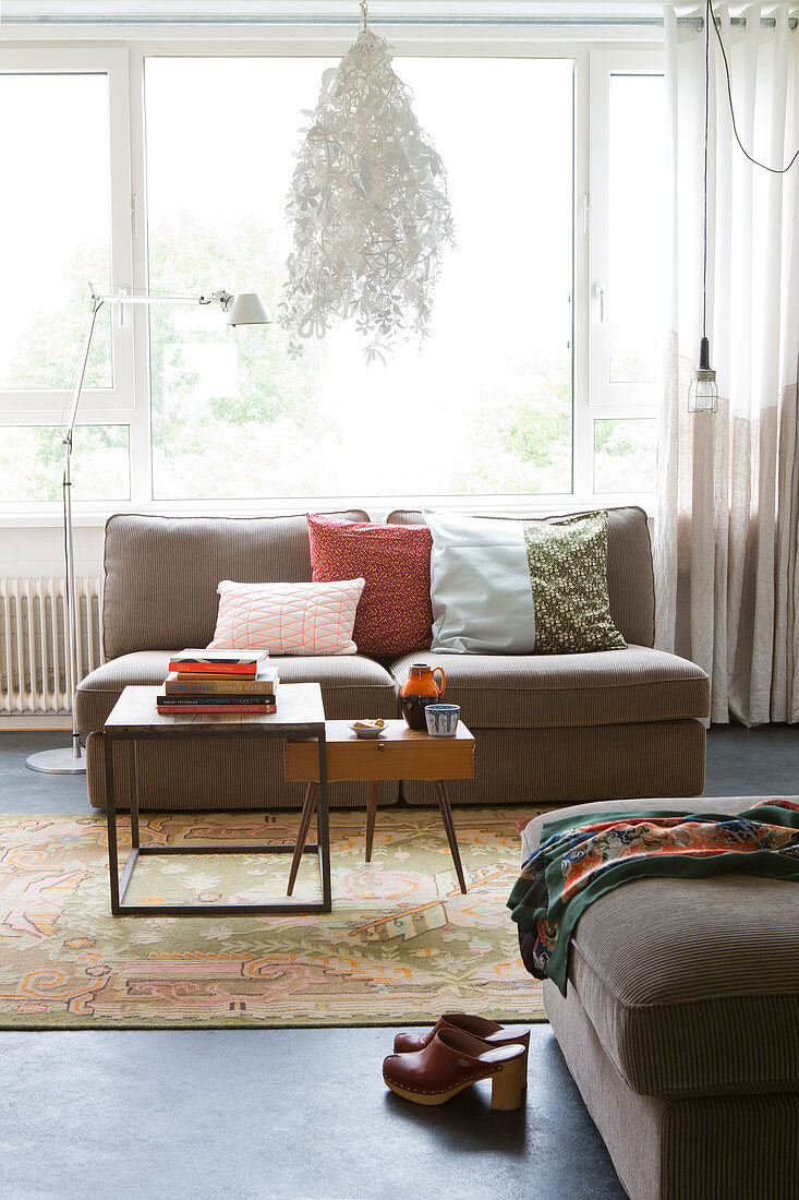 Scatter cushions on sofa and retro coffee table in front of window in living room