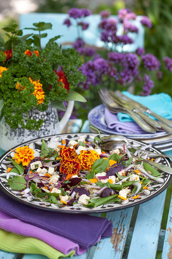 Salat mit Studentenblumen und Strauß aus Petersilie auf dem Gartentisch