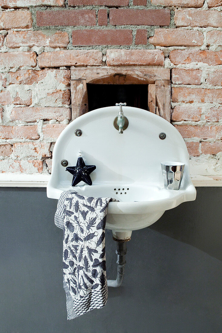 Old wash basin on a brick wall with a gray wall below the chair rail