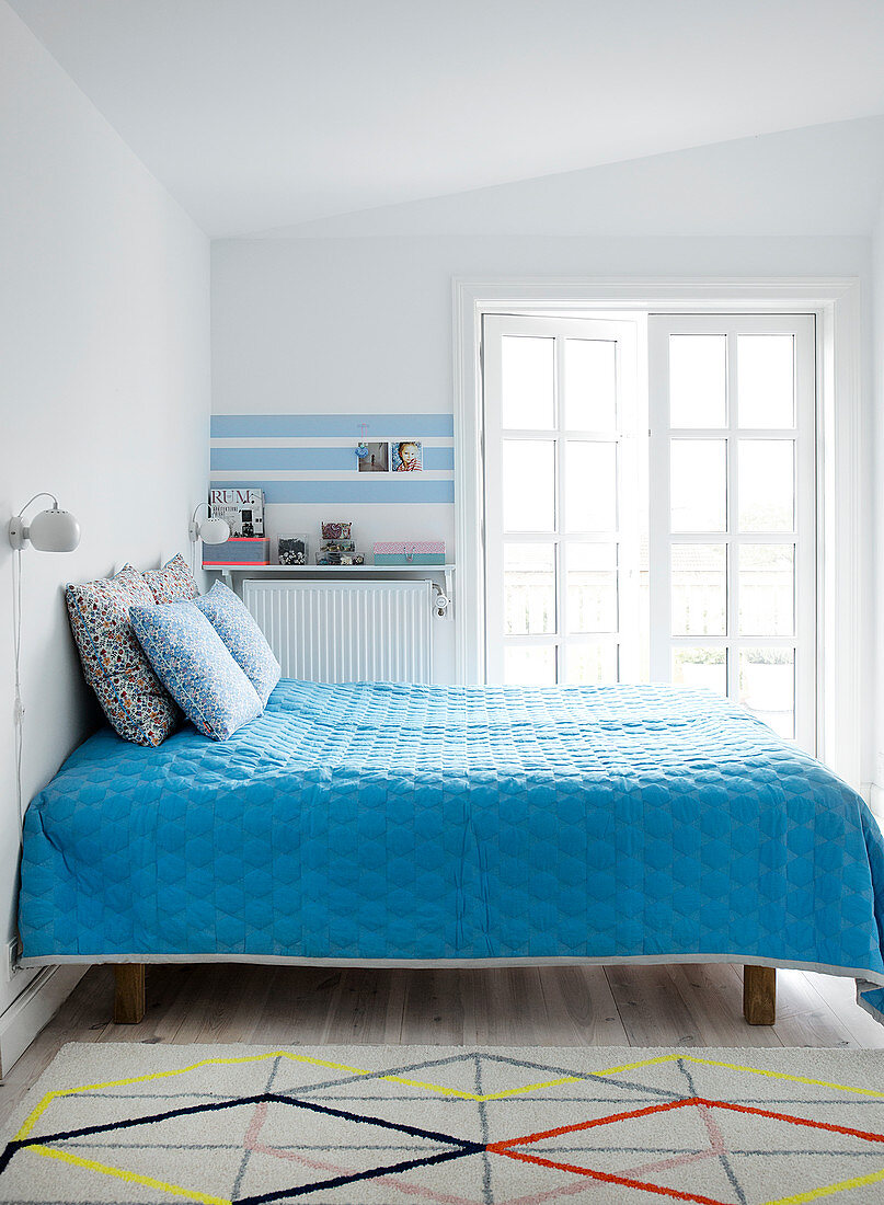 Blue bedspread on a bed in a simple bedroom
