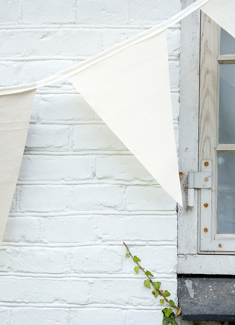 Textile bunting hung from a white brick wall