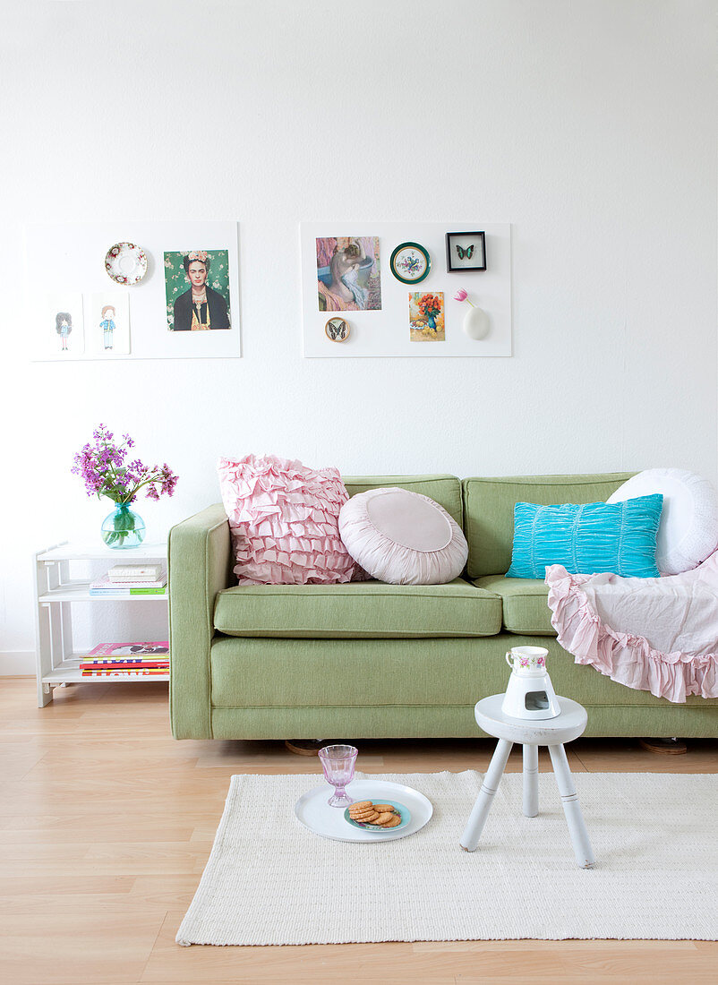 Romantic pillows on the green sofa under two mood boards