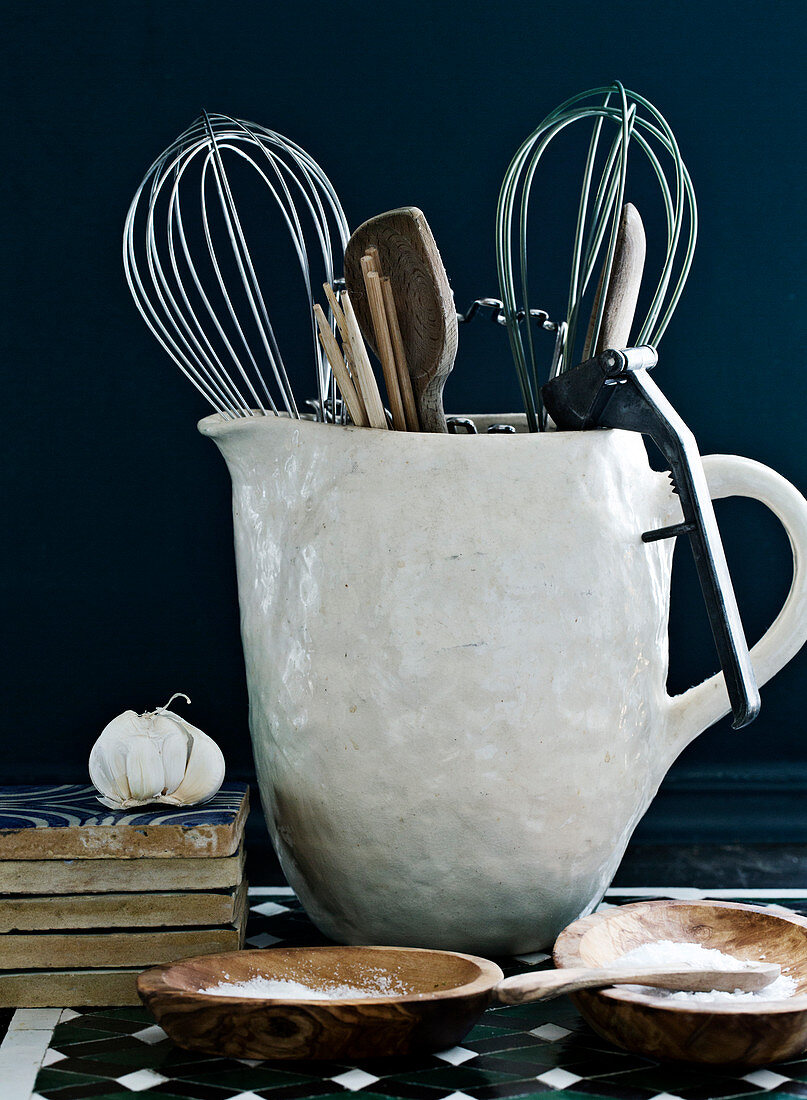 Kitchen utensils in a rustic pitcher, salt in wooden bowls
