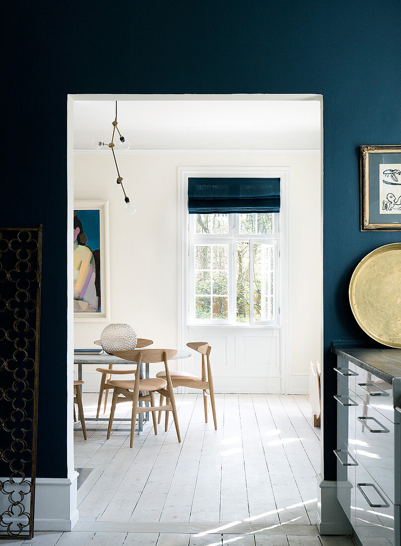 Blick aus der Küche mit dunkelblauer Wand ins helle Esszimmer