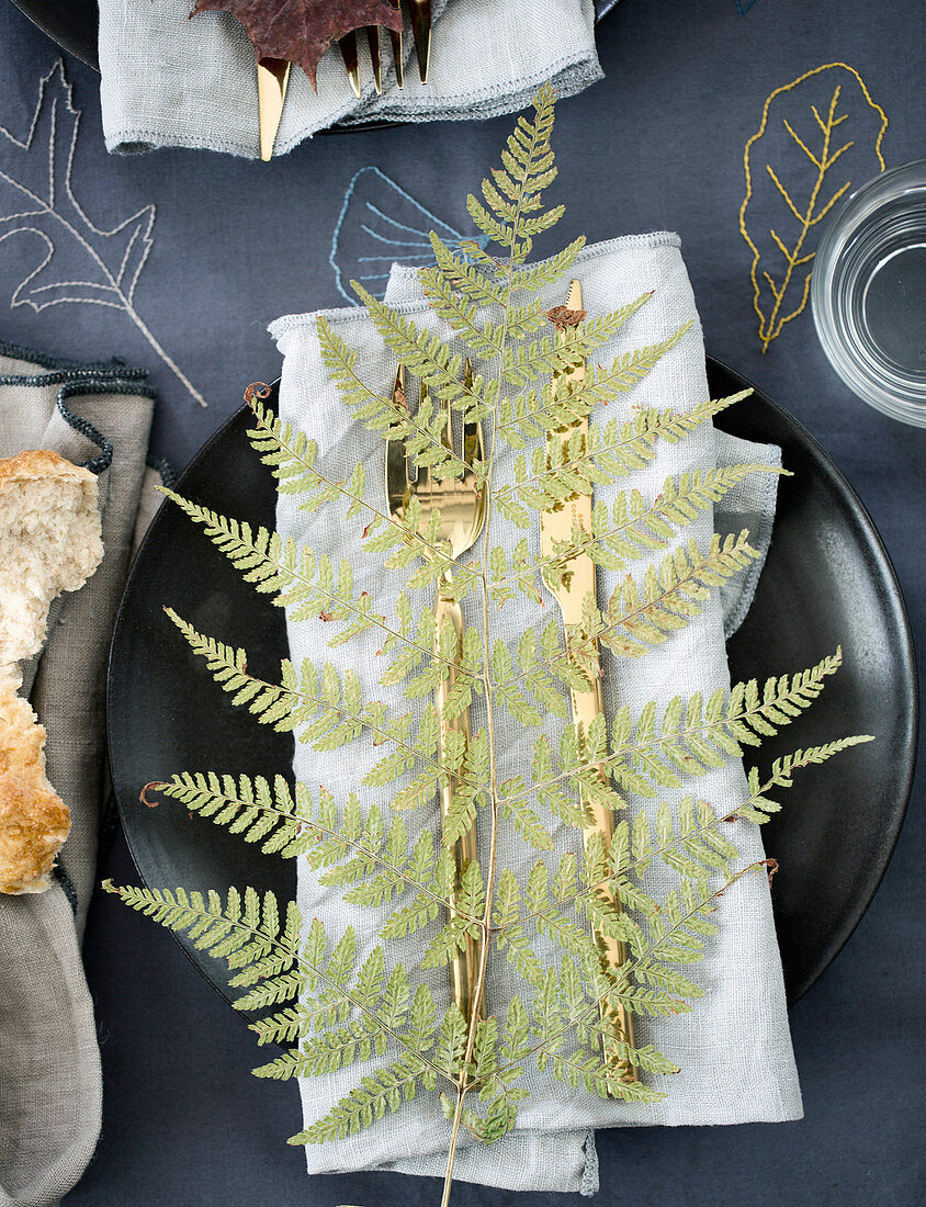 Place setting decorated with ferns on an embroidered tablecloth