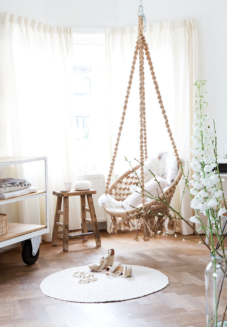 Macrame hanging chair above the round carpet