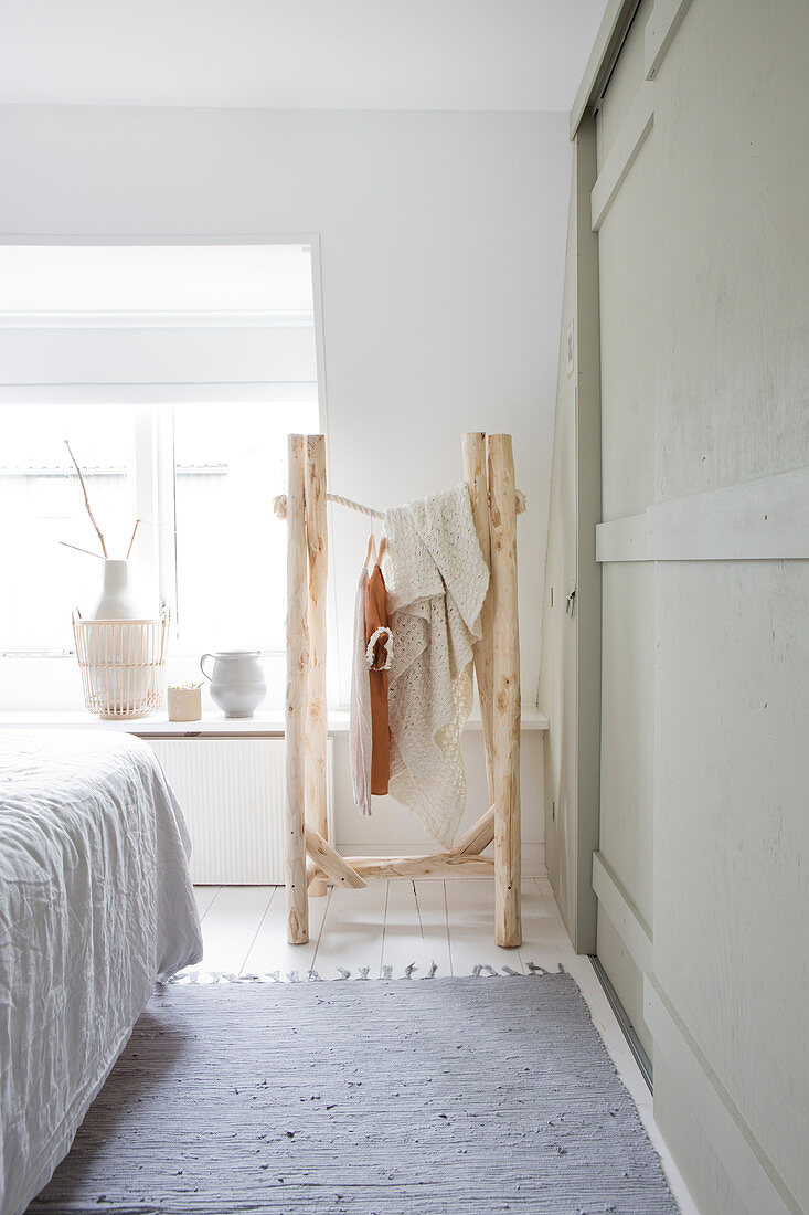 Clothes rack made of branches in a white bedroom