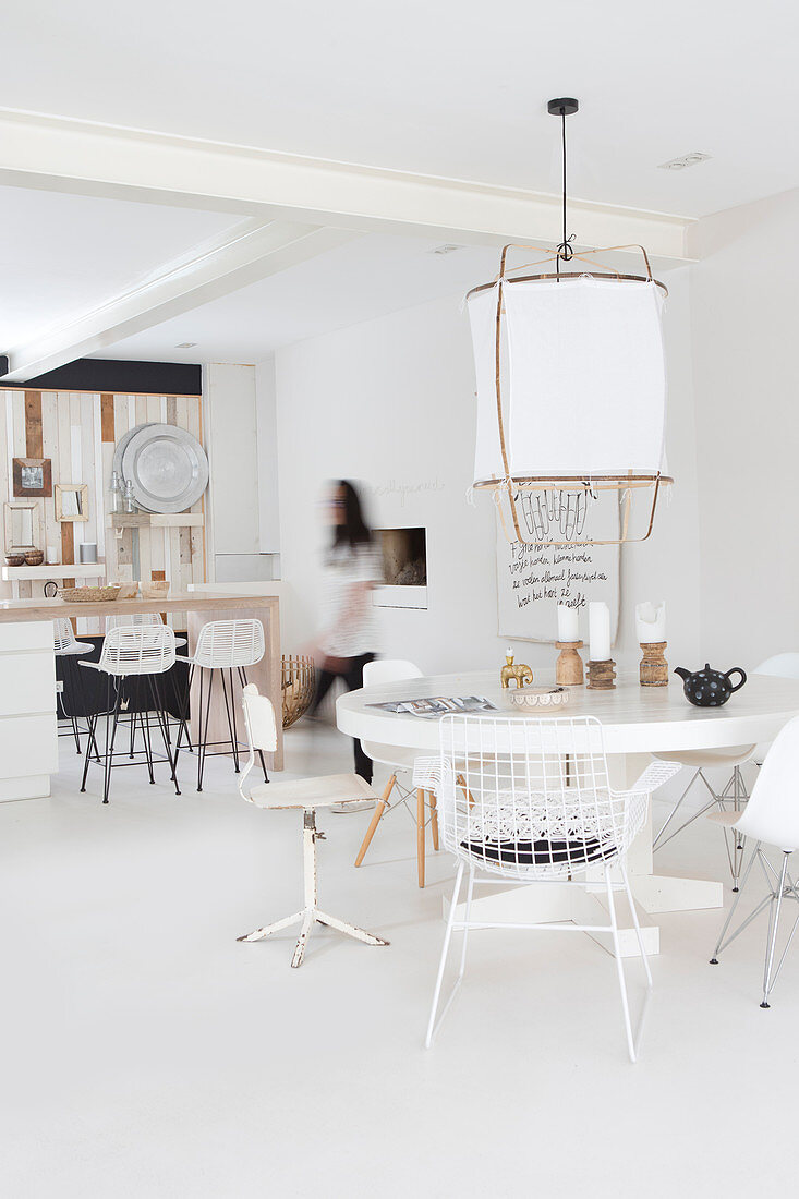 Runder Tisch mit verschiedenen Stühlen in weißem, offenem Wohnraum
