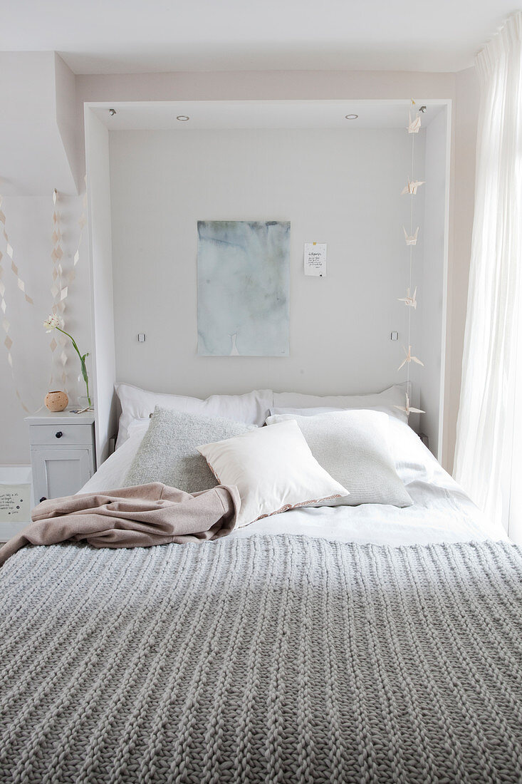 A grey knitted blanket on a double bed