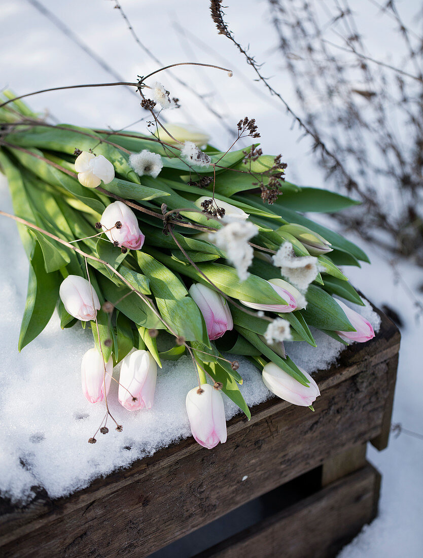 Bouquet of tulips on a wooden box in the snow
