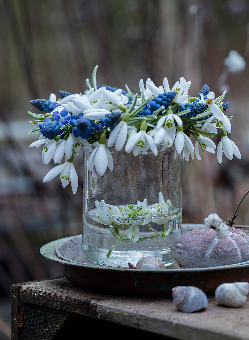 Wreath of grape hyacinths and snowdrops on a glass vase