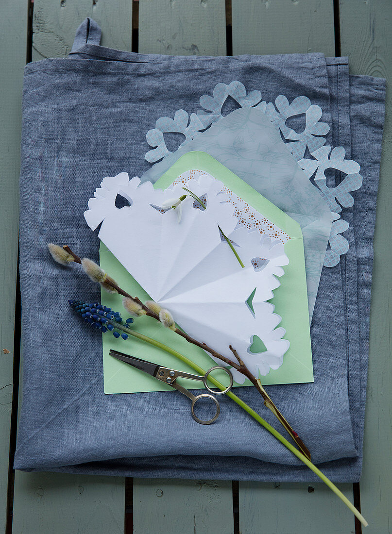 Schneeflocke aus Papier, Traubenhyazinthe und Weidenkätzchen auf einem Briefumschlag