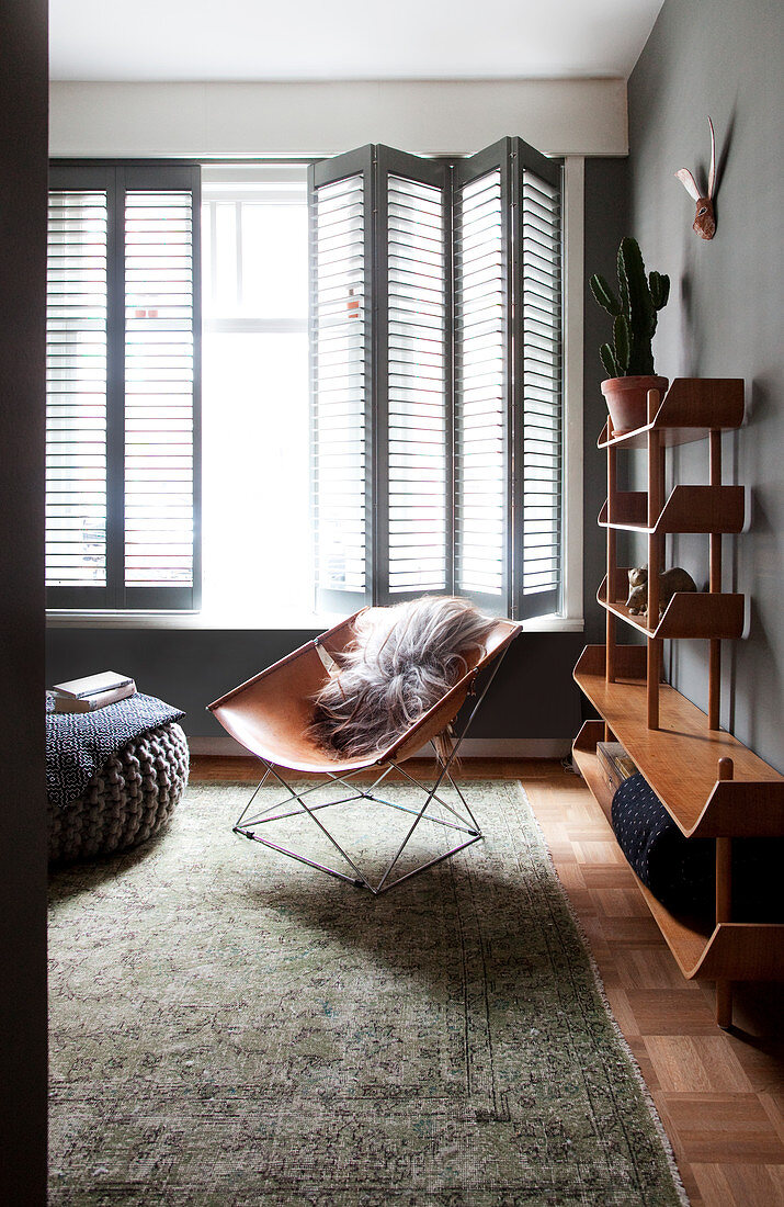 Klassiker Lederstuhl und Schrankregal im Wohnzimmer mit Fensterläden