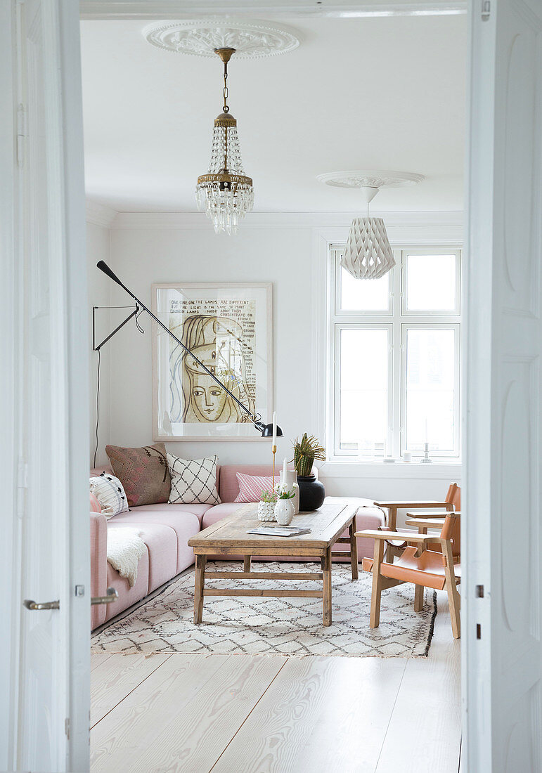 Rosa Polstergarnitur, rustikaler Couchtisch und Lederstühle im Wohnzimmer