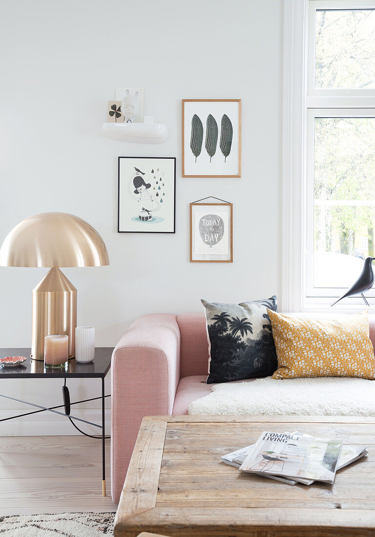 Rosa Polstergarnitur, goldene Tischlampe und rustikaler Couchtisch im Wohnzimmer