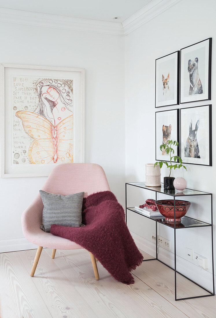 Rosa Polsterstuhl mit Kissen und Decke, Konsolentisch und Bilder an der Wand