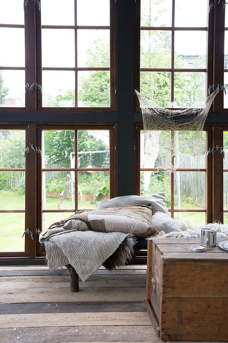 Holztruhe und Tagesbett mit Decken im Gewächshaus