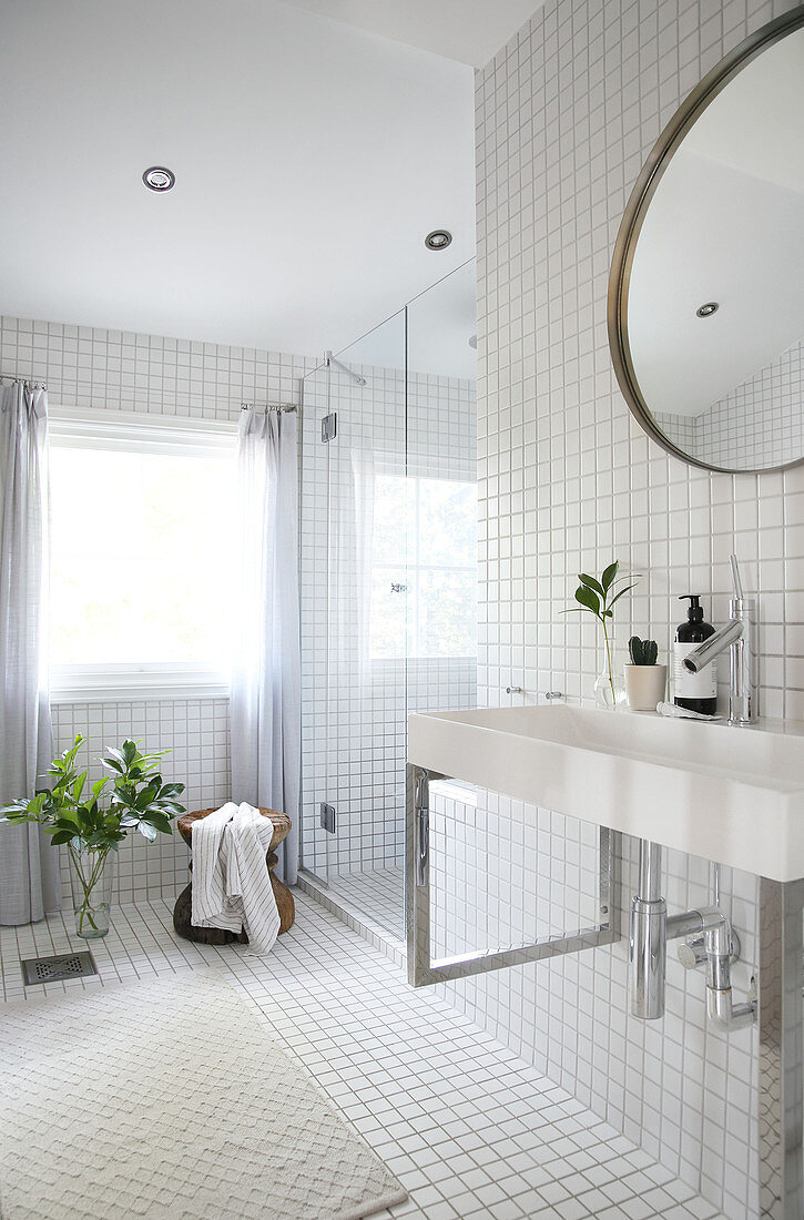 A washbasin and a round table in a white tiled bathroom