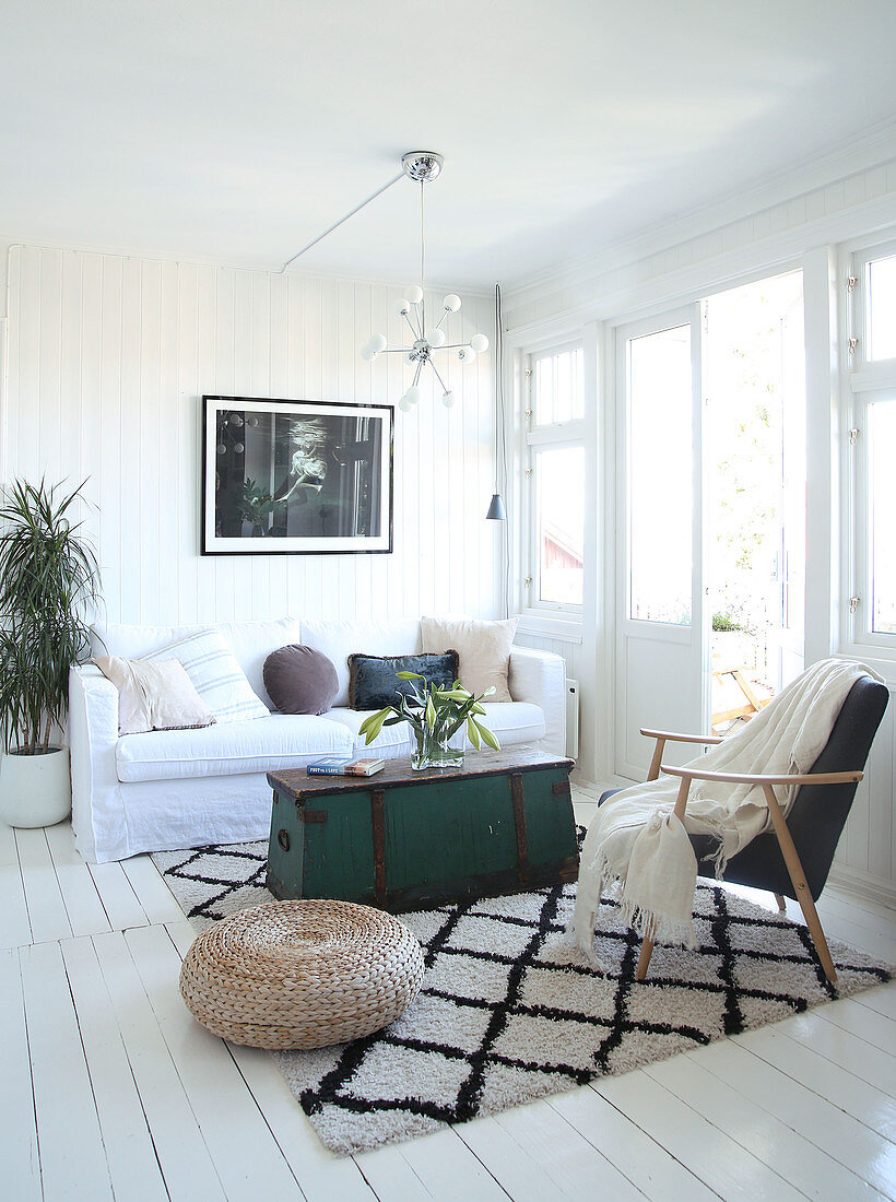 Vintage Holztruhe als Couchtisch und Sessel auf Teppich mit Rautenmuster im Wohnzimmer