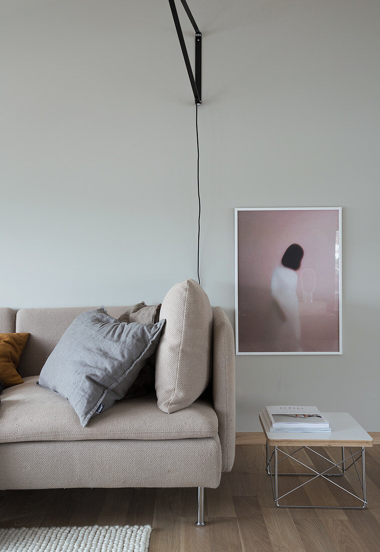 A light upholstered sofa, a side table and photo art on the wall