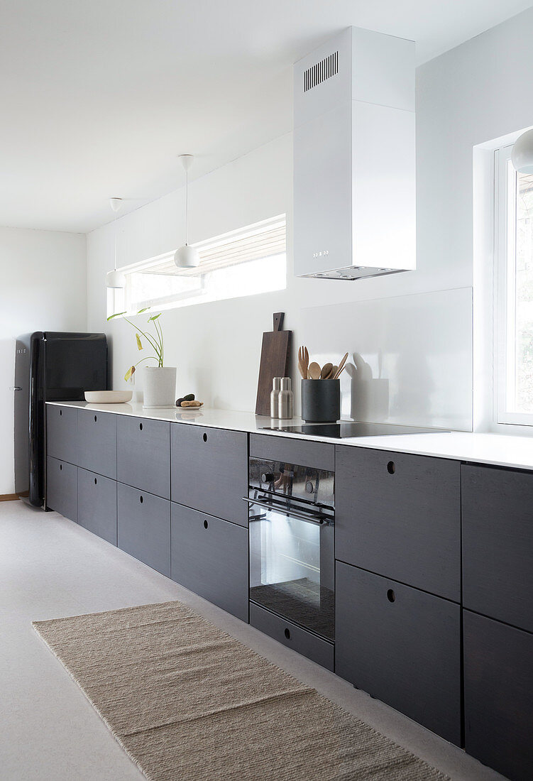 A kitchenette with dark cupboards in a white kitchen