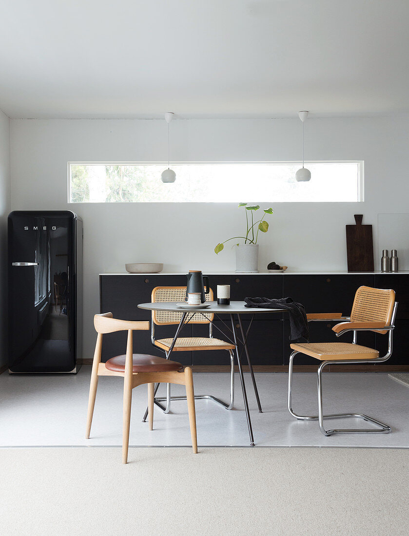 A round table with classic chairs in front of a dark kitchenette