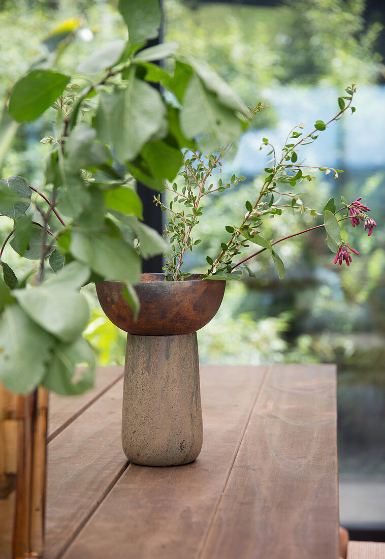 Vasen mit Blätterzweigen auf Holztisch