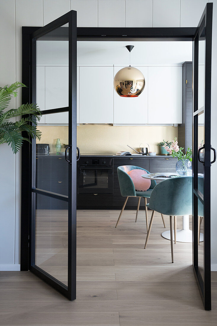 Blick durch offene Glastür in die Küche mit rundem Tisch und Schalenstühlen
