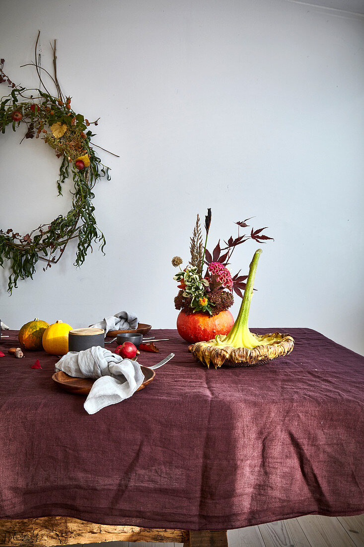 Herbstlicher Strauß in ausgehöhltem Kürbis und getrocknete Blüte auf Tisch