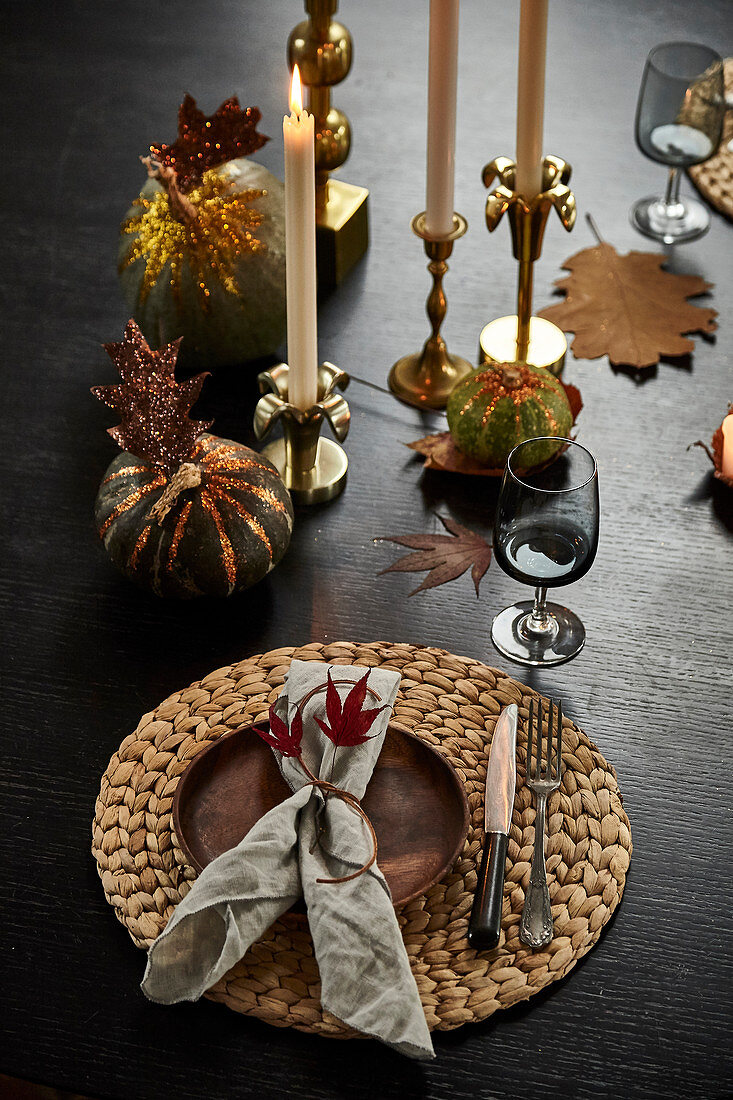 Gedeck und Kerzen auf herbstlich dekoriertem Tisch