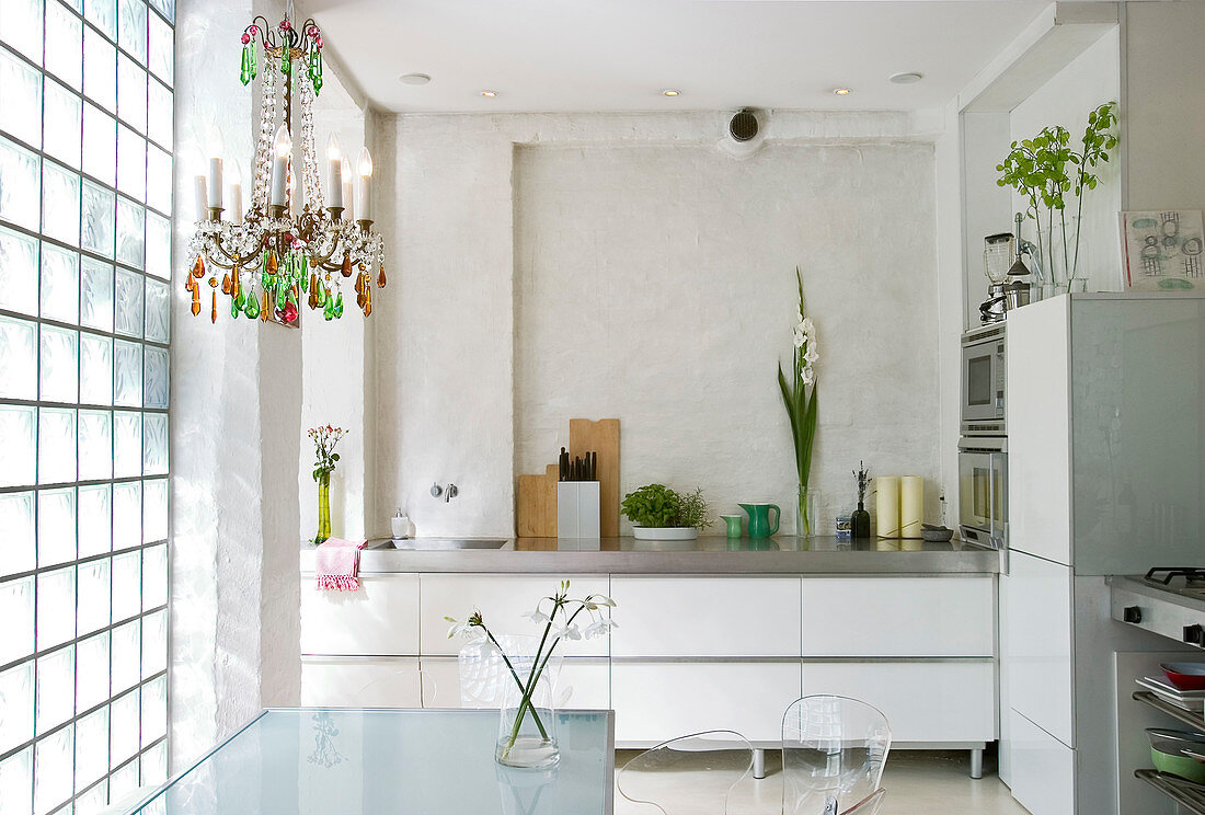 A chandelier above the dining table on the glass block wall in a modern kitchen