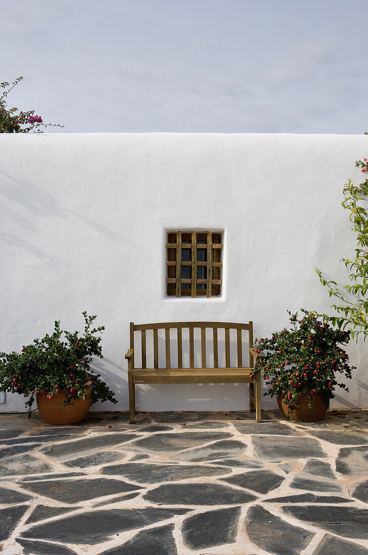 A garden bench under a lattice window of a Mediterranean house