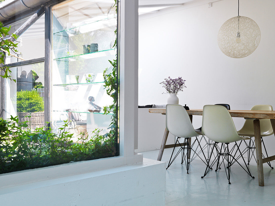 Schalenstühle am Tisch im Esszimmer mit weißem Boden und Fensterfront