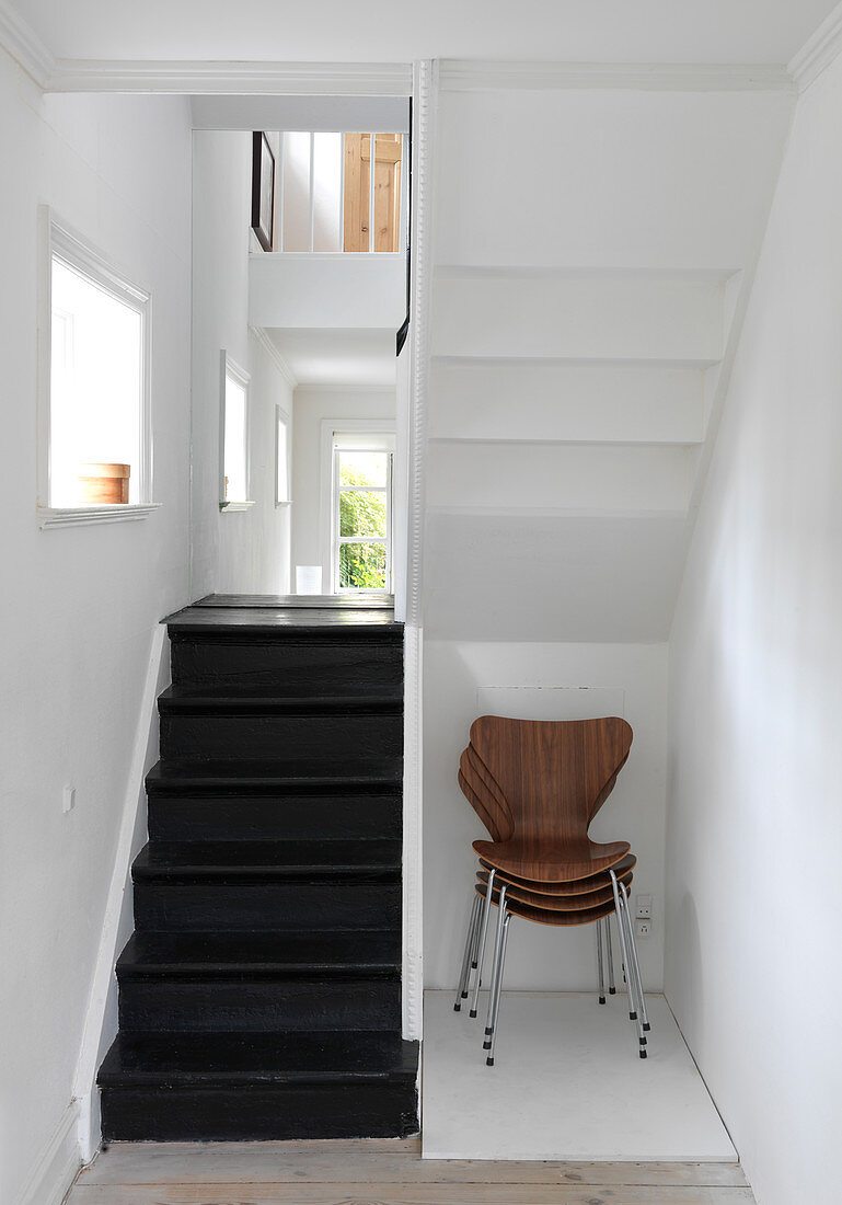 Stapel Designerstühle unter der Treppe mit schwarzen Stufen