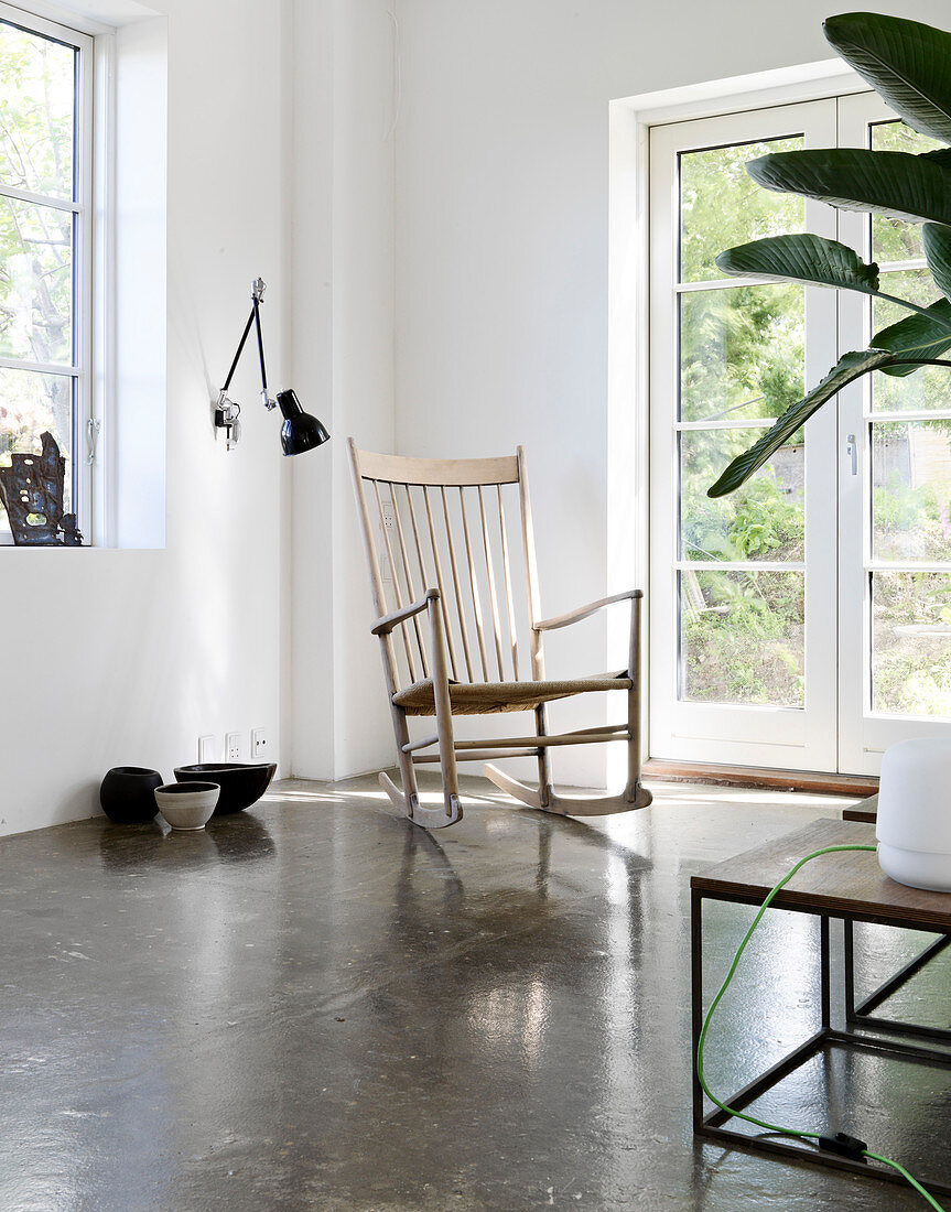 Rocking chair in front of garden door in minimalist living room with concrete floor