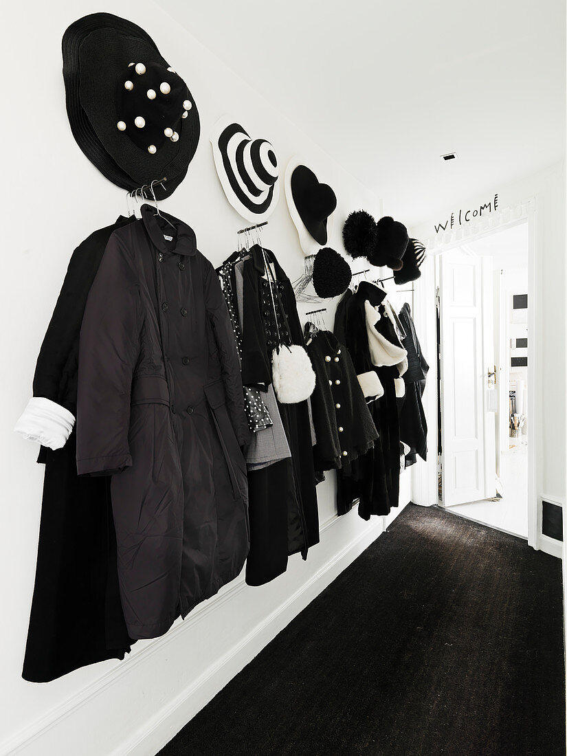 Coat hooks in a hallway with black jackets, coats and hats