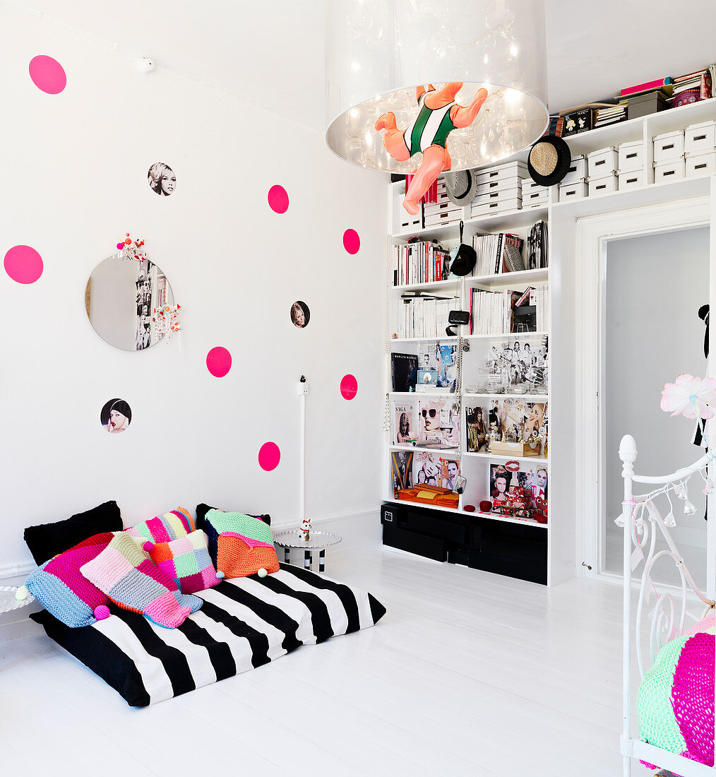 reading nook in front of the wall with pink dots and the shelf in the nursery