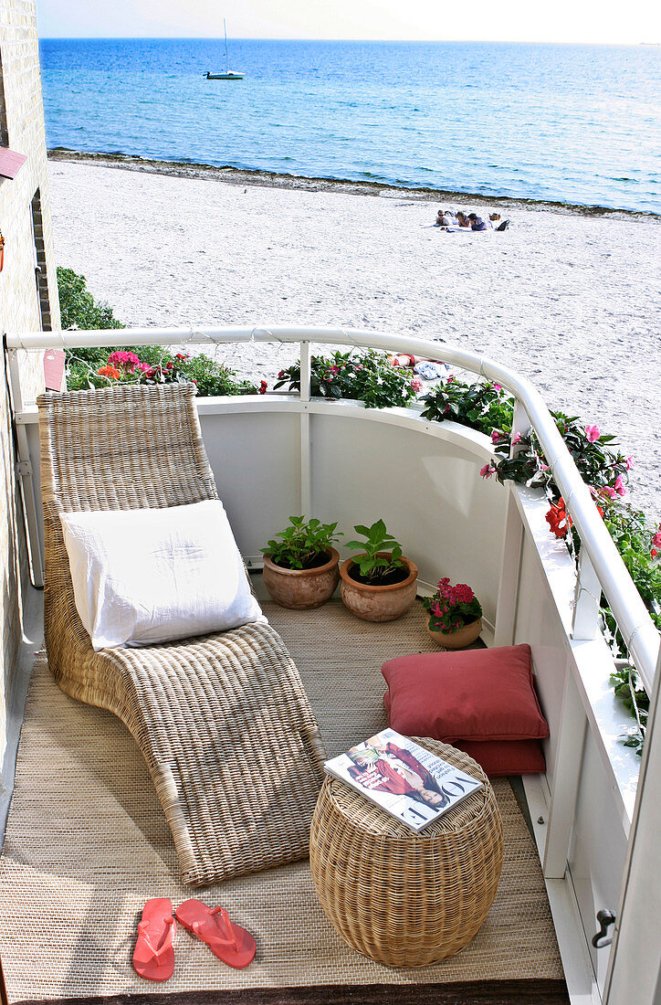 Liegestuhl und Hocker aus Korb auf dem Balkon mit Meerblick