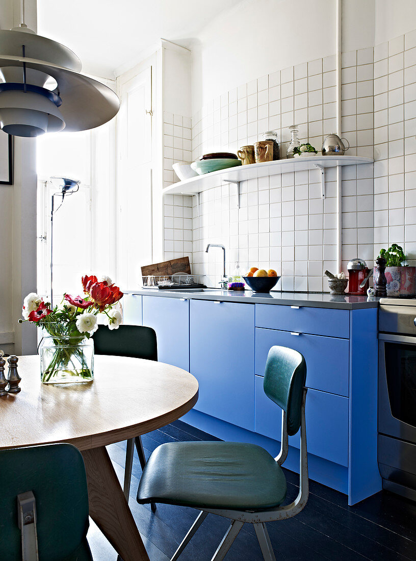 Runder Tisch und Retrostühle in der Wohnküche mit blauen Fronten