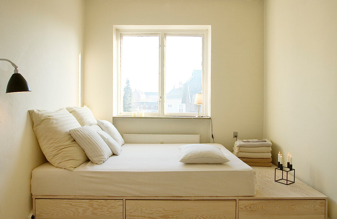 A mattress on a platform bed with drawers in the narrow bedroom