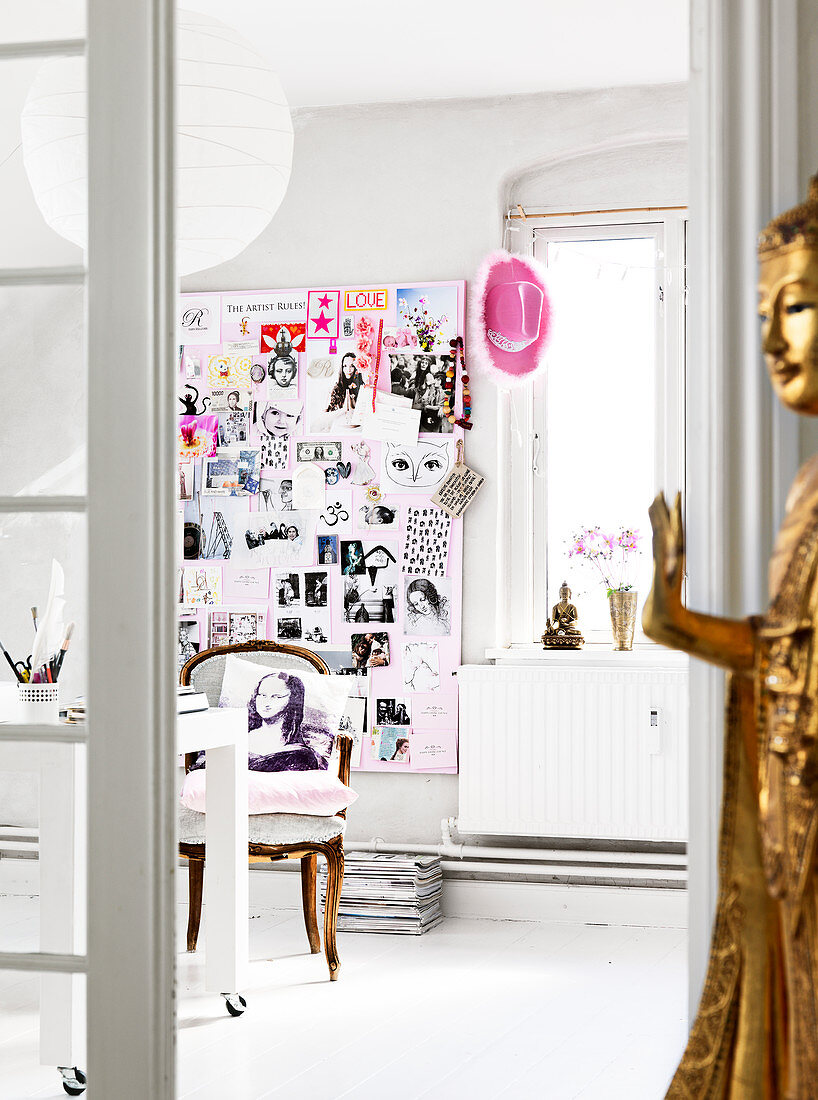 Goldener Buddha vor der offenen Tür zum Arbeitszimmer mit Collage