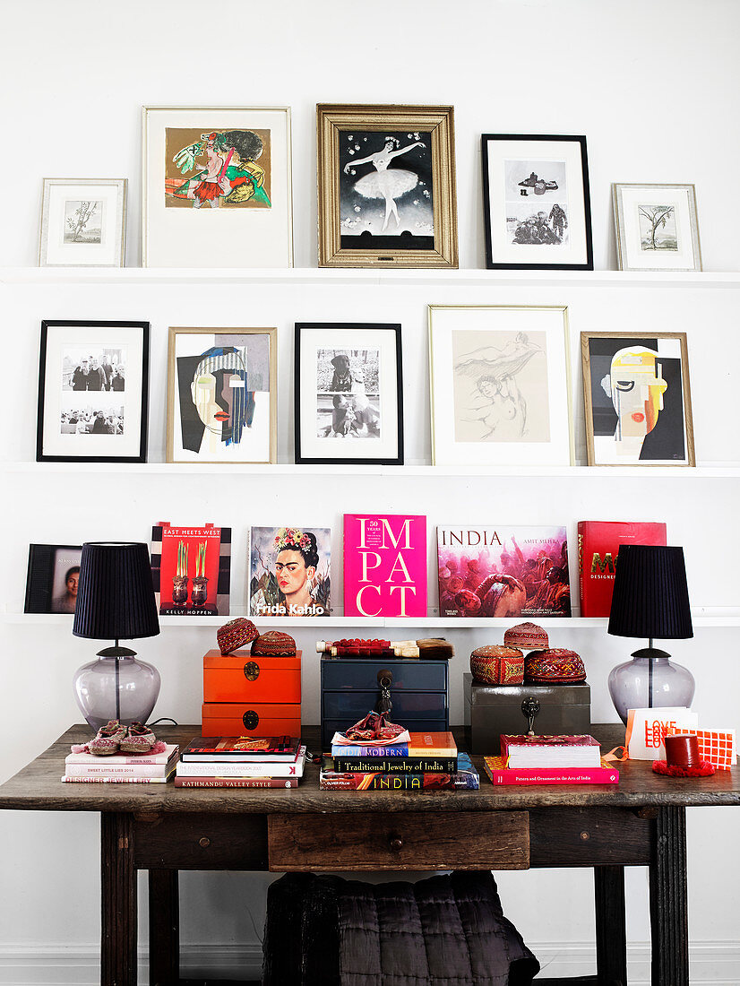 Shelves with photos, artwork, and books over old wooden desk