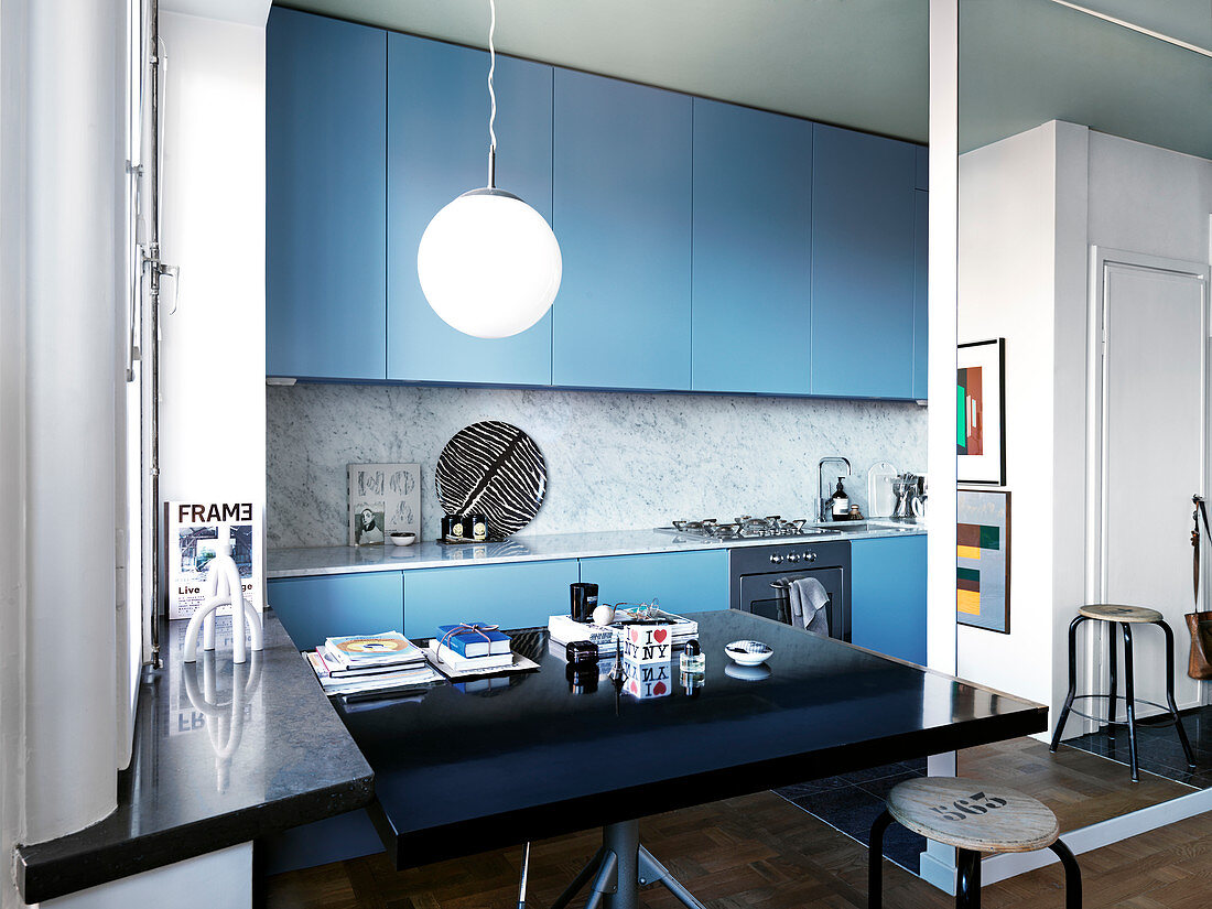 Schwarzer Esstisch in moderner offener Küche mit blauen Fronten