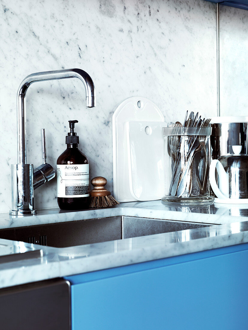 Sink and splash guard made of marble in the kitchen with blue cabinet fronts